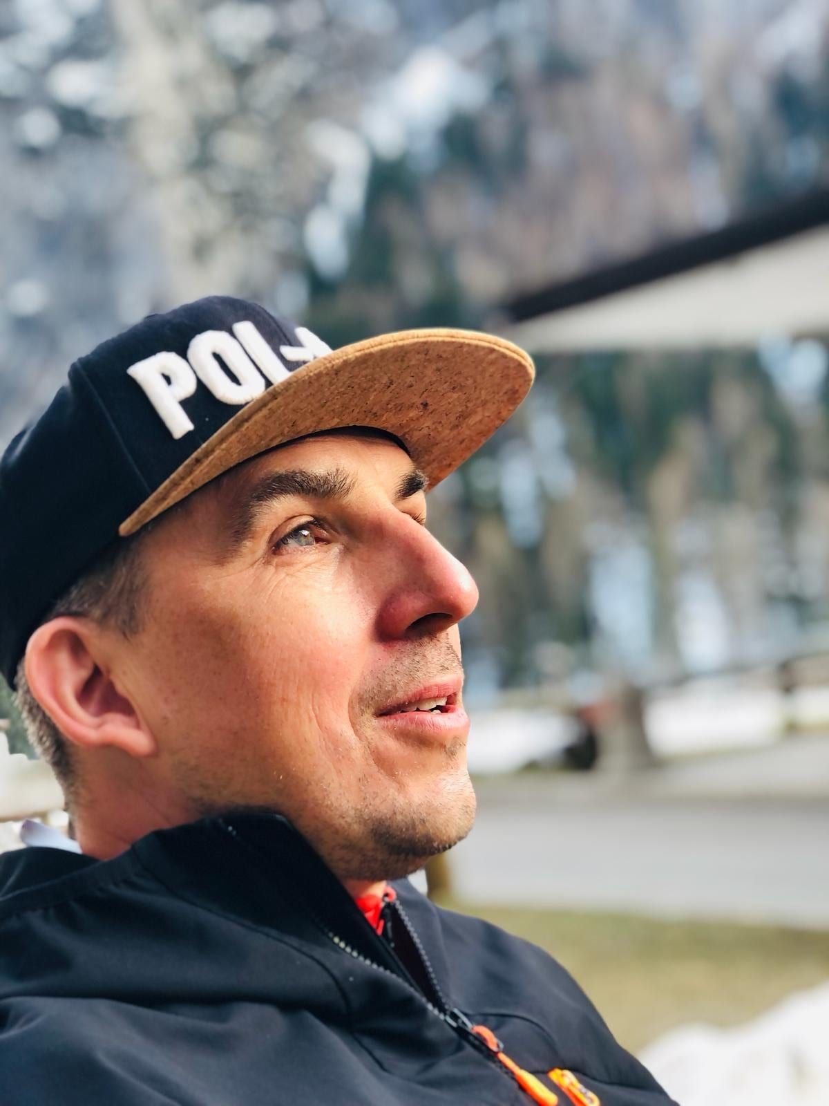 Łukasz Kękuś in a Pol-Ski cap, portrait with mountains behind