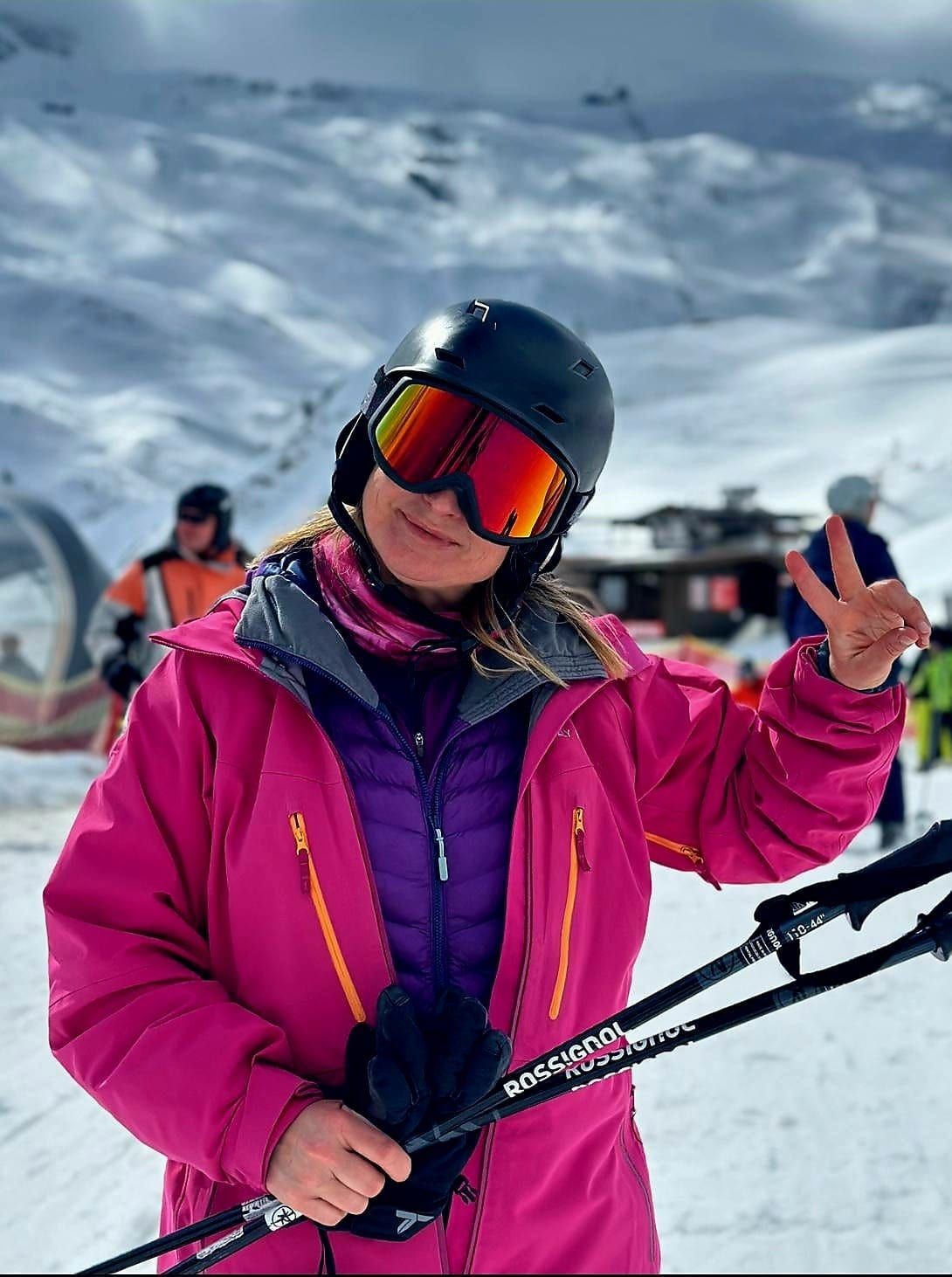 Paulina in a pink jacket and ski helmet holding ski poles