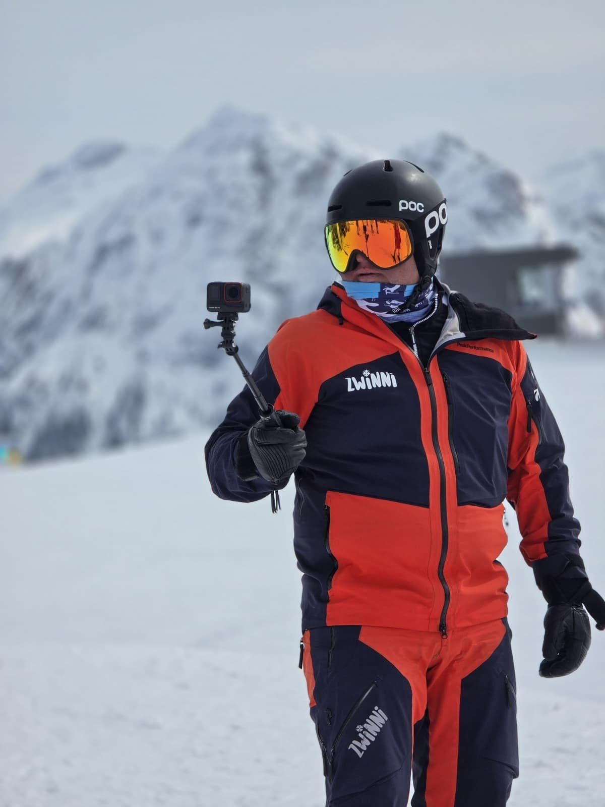 Wojtek Przygoda in a red and navy ski jacket holding a camera pole